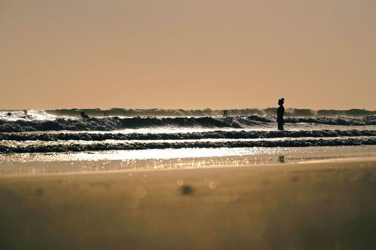 Silhouette man standing on beach against clear sky