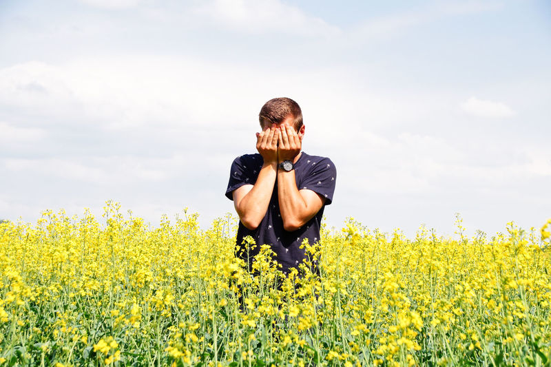 Man standing amidst yellow flowers on oilseed rape field