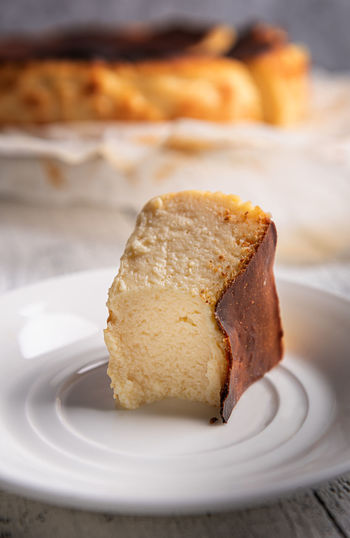 Close-up of bitten portion of basque burnt cheesecake on white plate. 