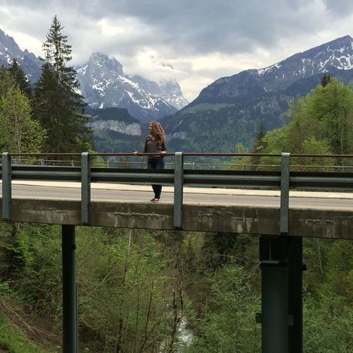 Woman standing on bridge against mountains