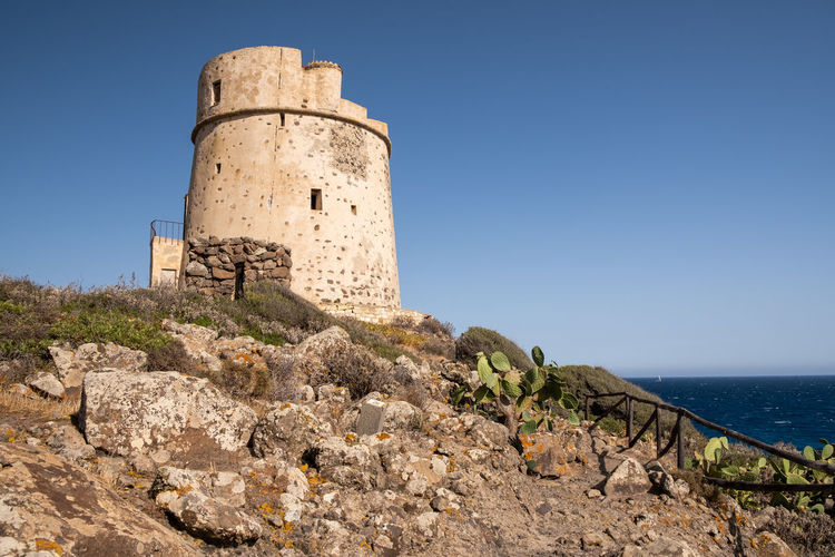Lighthouse by sea against clear sky