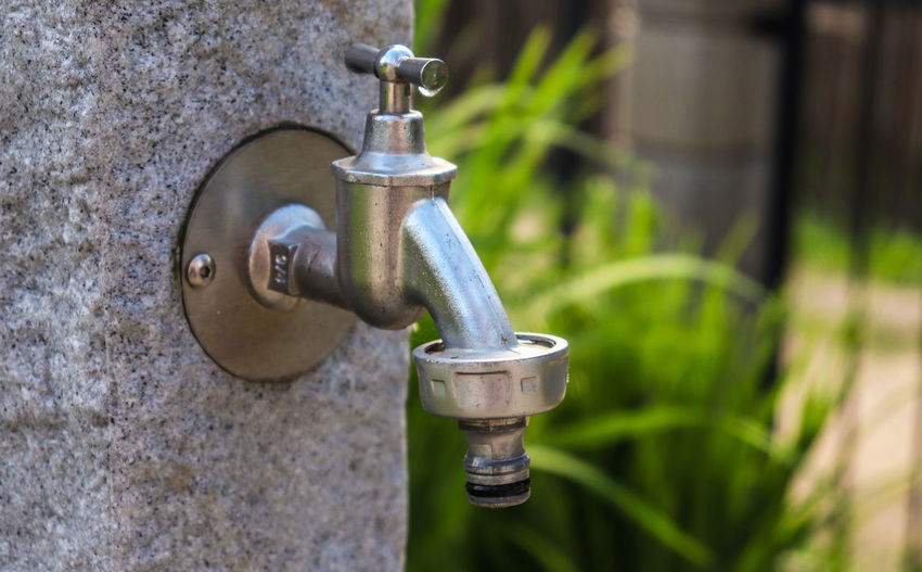 Close-up of old faucet against wall