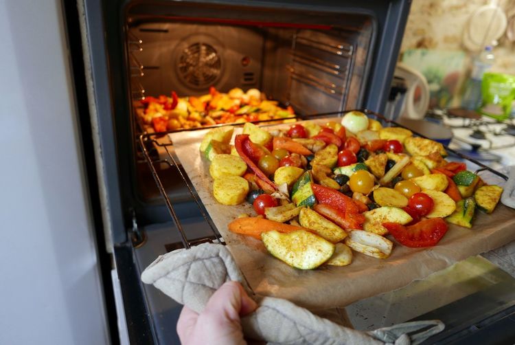 Cropped hand putting vegetables in microwave