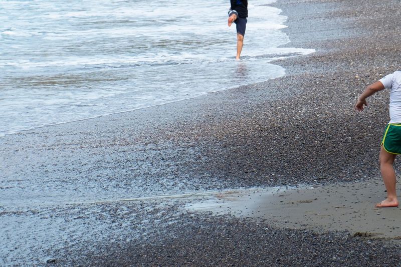 Low section of people walking on wet beach