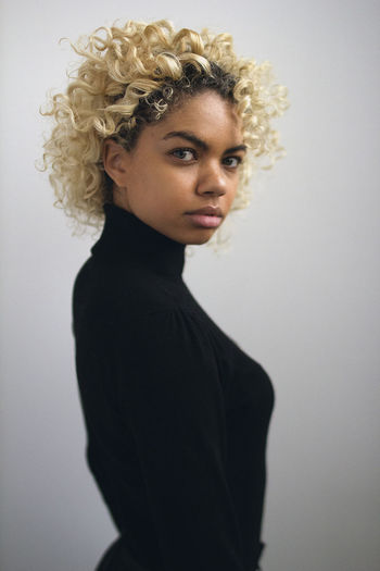 Portrait of young woman standing against white background