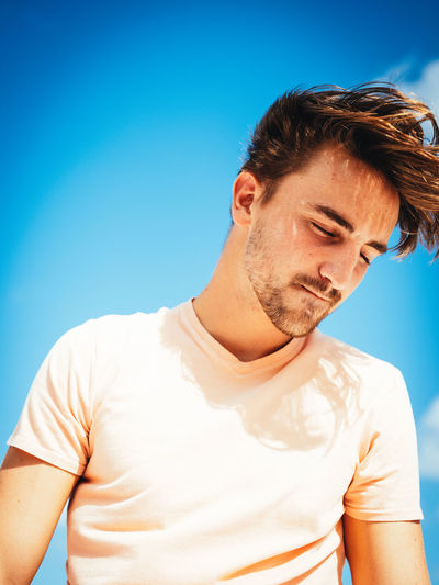 Young man standing against clear blue sky