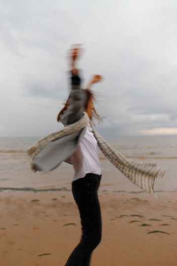 Blurred motion of woman on beach against sky