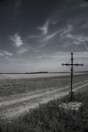 Cross by field against sky
