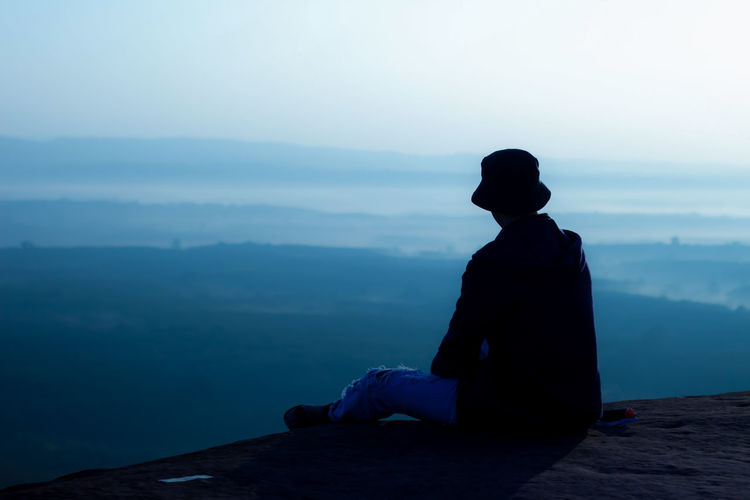 Man sitting and watching the sunrise in the morning on the cliff