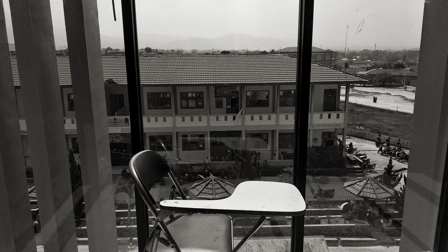 Empty chairs and tables against buildings seen through window