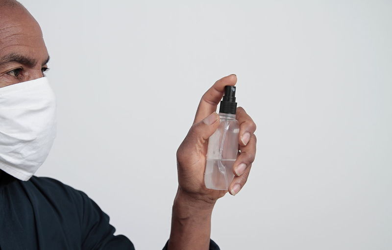 Portrait of man holding bottle against white background