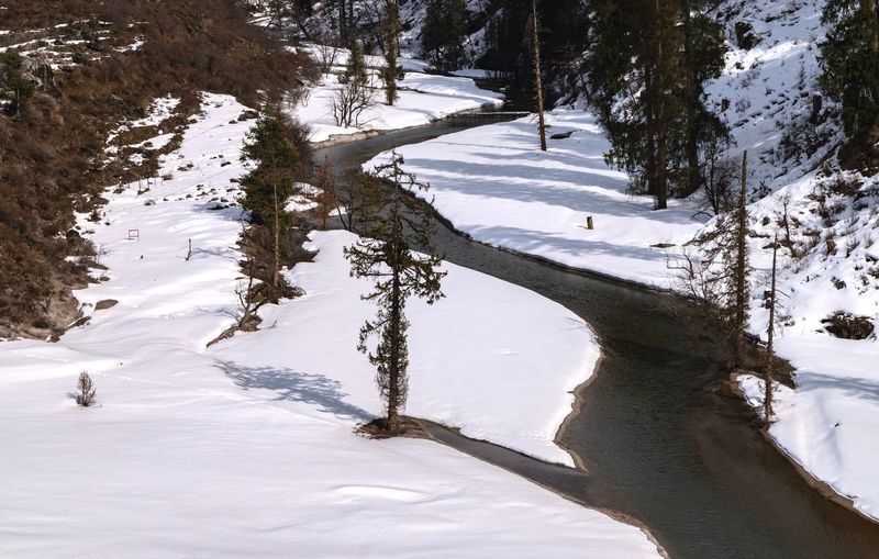 Beas river flowing through snow in himalayan mountain valley