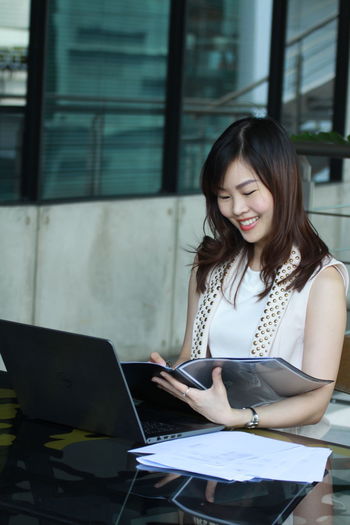 Smiling businesswoman reading file while sitting at desk