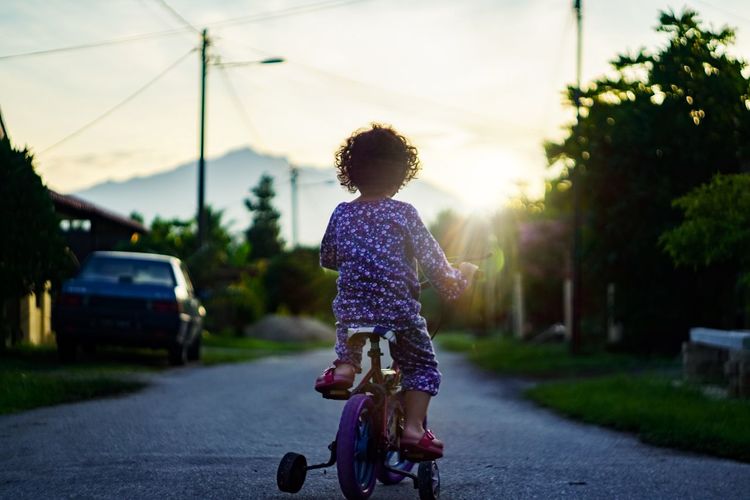 Rear view of girl riding bicycle on road
