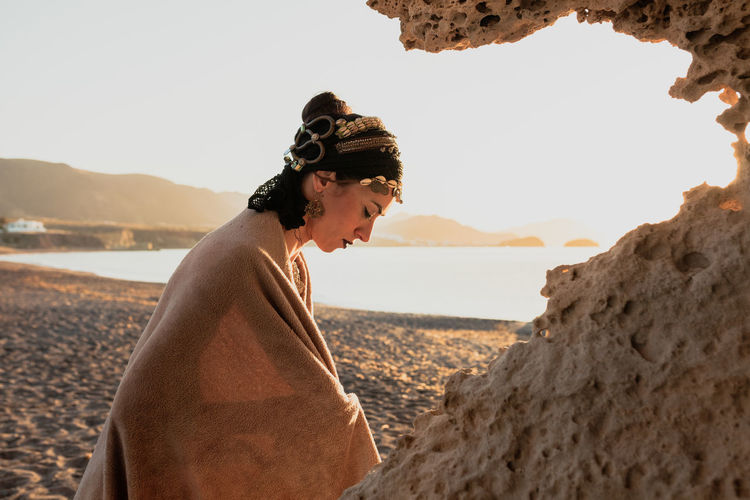 Side view of woman on beach against sky