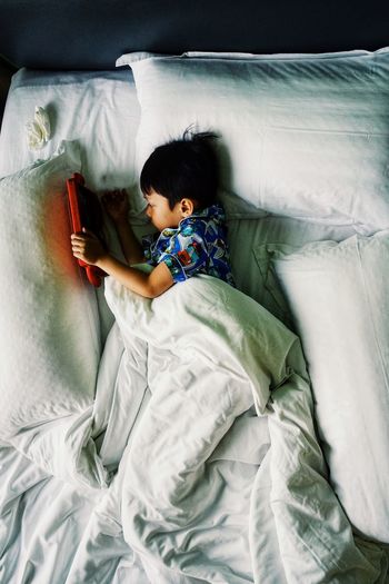 High angle view of boy resting on bed at home