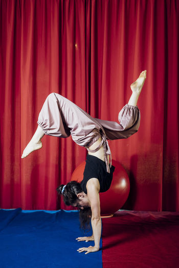 Female acrobat doing handstand on circus stage