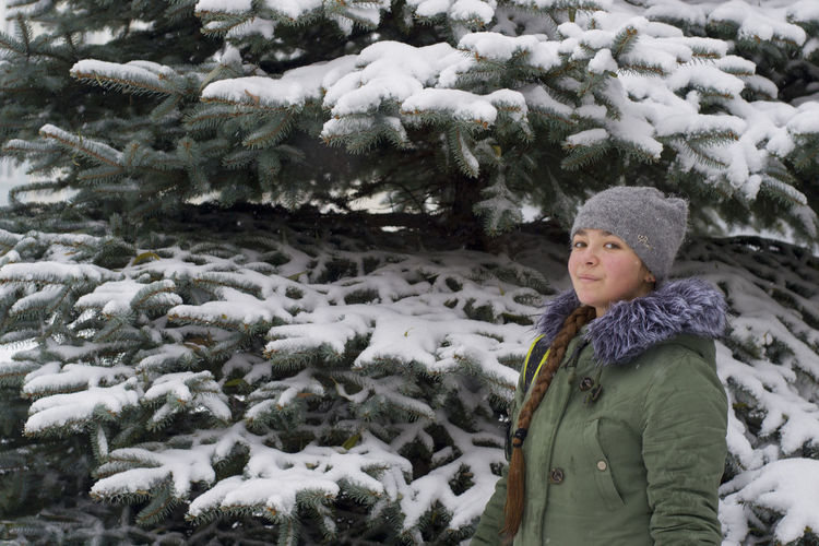 Portrait of girl standing in front of snow covered tree
