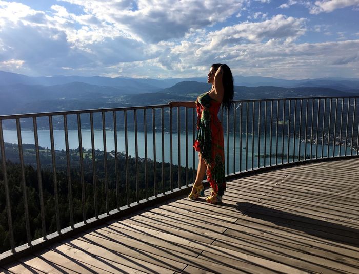 Full length of woman standing at pyramidenkogel tower against cloudy sky