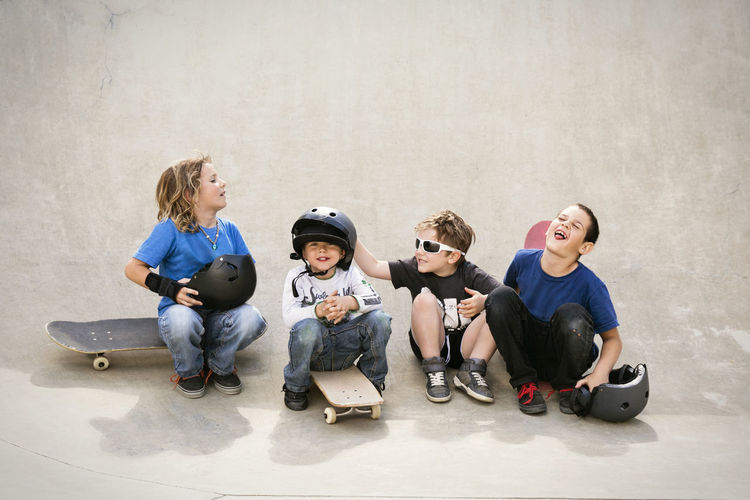 Cheerful boys talking while sitting on skateboard ramp