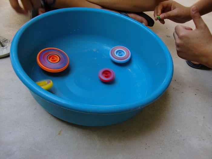 Cropped image of kids playing with spinning tops in plastic basket