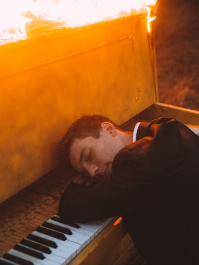Young man sleeping on piano