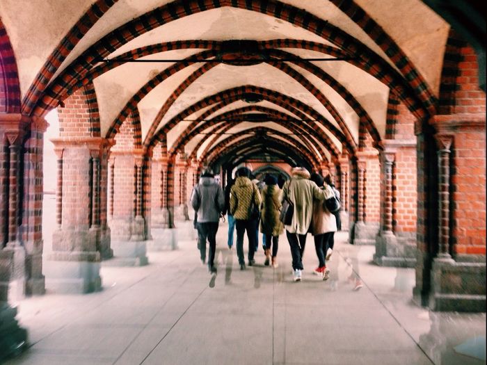 Full length rear view of people walking in building corridor