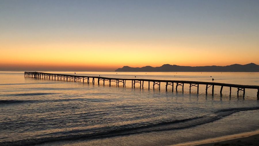 Pier over sea against clear sky during sunset