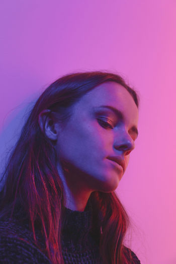 Close-up portrait of beautiful young woman against pink wall