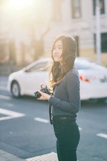 Side view of young asian girl standing on street in sunshine