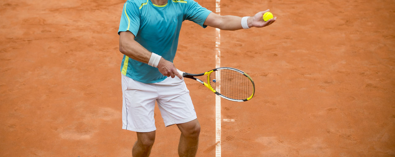 Midsection of man playing tennis