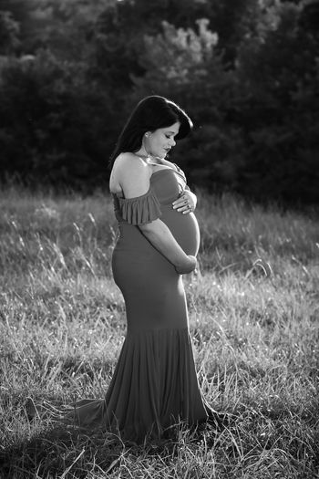 Side view of woman with child in grassy field black and white