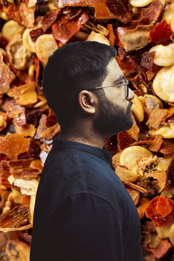 Side view of man standing by autumn leaves