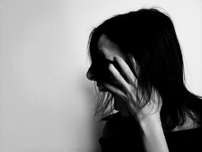 Close-up of woman screaming against wall