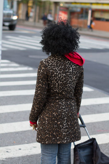Rear view of woman crossing road in city