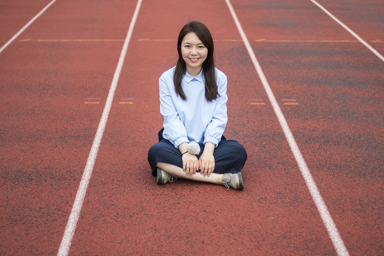 Portrait of woman sitting on running track