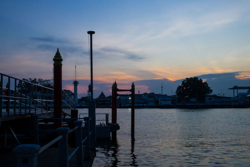 Scenic view of river by buildings against sky during sunset