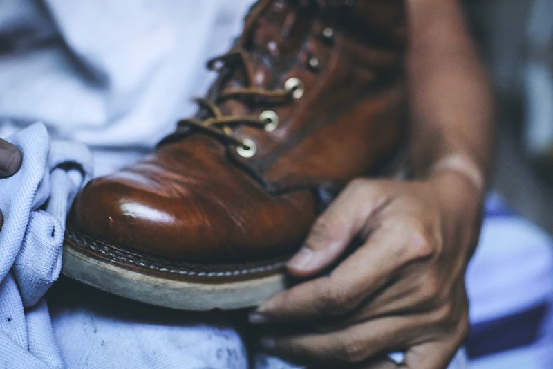 Cropped image of person polishing boot