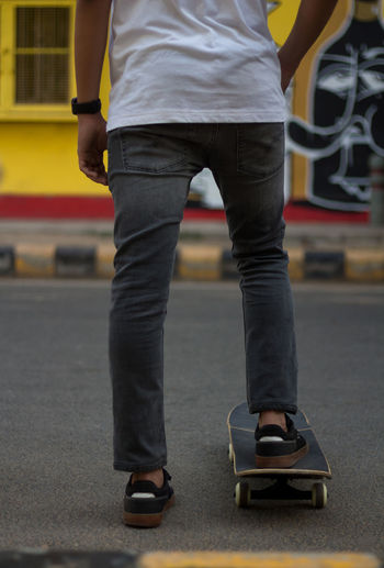 A young man standing while keeping one of his foot on a skateboard.