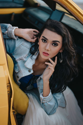 High angle portrait of young woman sitting in convertible car