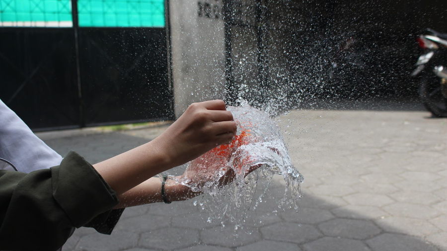 Midsection of person splashing water fountain