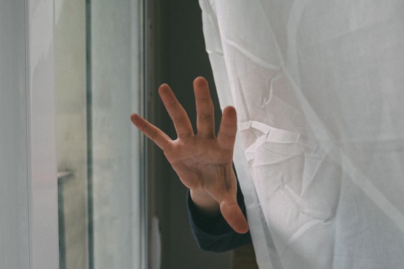 Close-up of human hand against curtain