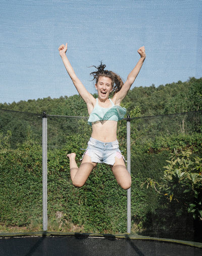Full length of happy young woman jumping outdoors