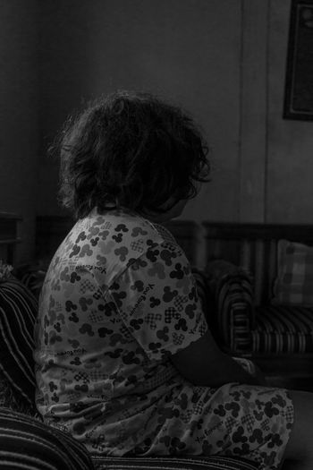 Rear view of woman sitting on bed at home