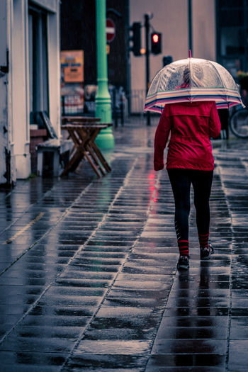 Rear view of woman walking on wet street during monsoon