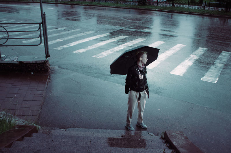 Full length of teenager girl standing on wet street during monsoon