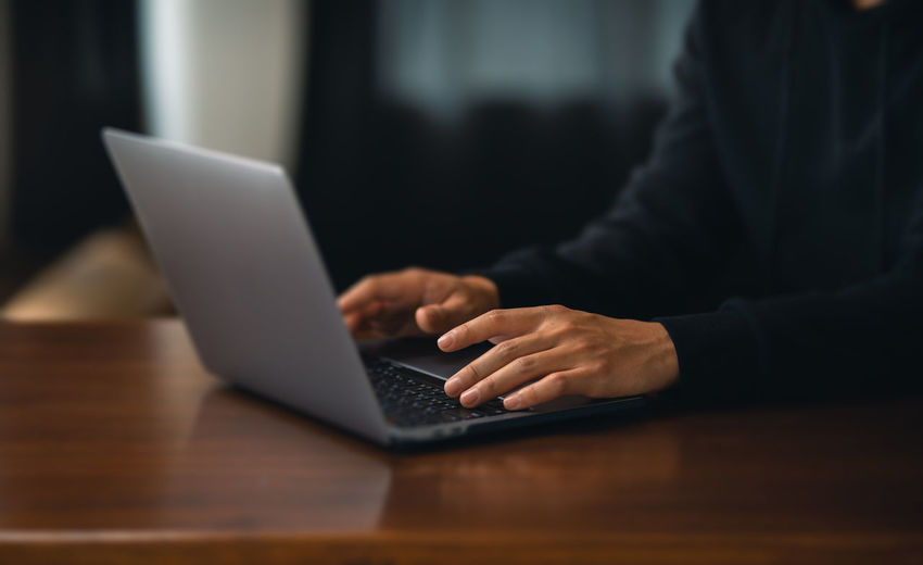Midsection of man using laptop on table