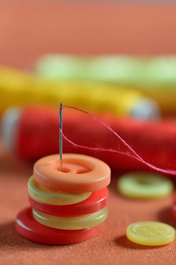 Close-up of sewing needle with button and thread spools on table