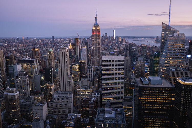 Aerial view of illuminated buildings in city against sky during sunset