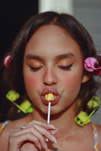 Close-up of young woman with eyes closed eating lollipop